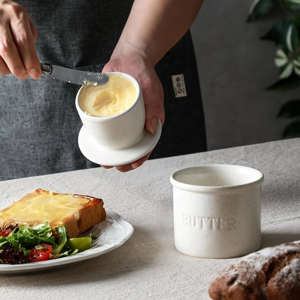 Hand spreading soft butter from the ceramic French butter crock