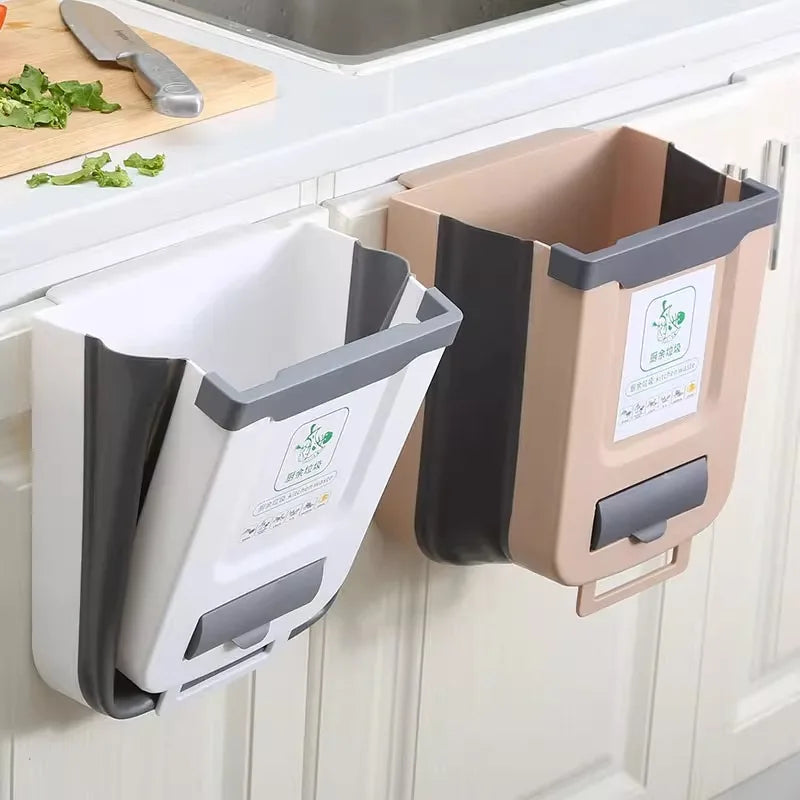 Wall-mounted folding kitchen trash bins in white and coffee colors hung on cabinet doors next to a kitchen sink