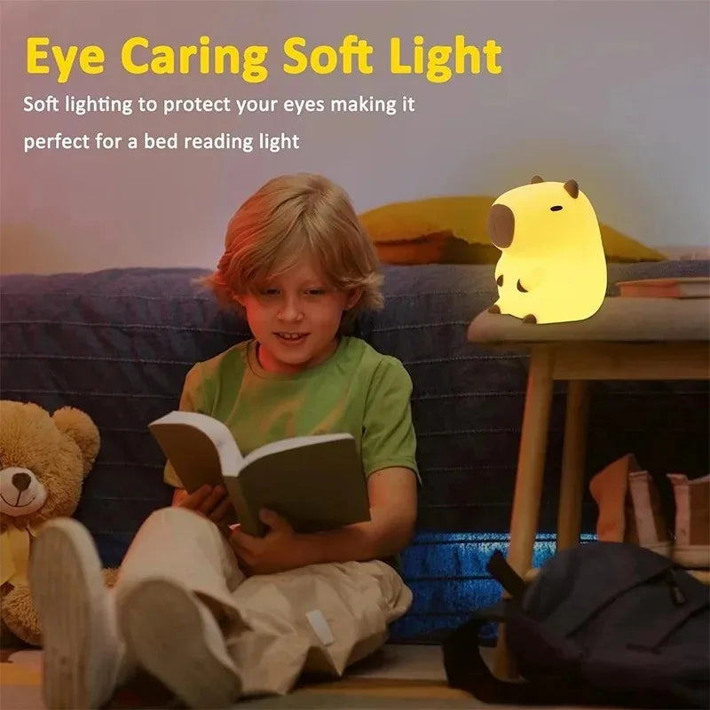 Child reading on the floor next to a capybara night light on a table