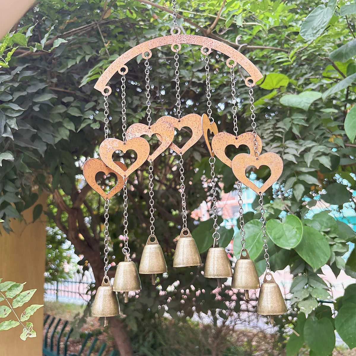 Metal wind chime with hanging heart shapes and bells displayed outdoors