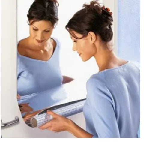 Woman applying an acrylic mirror sticker roll to a door