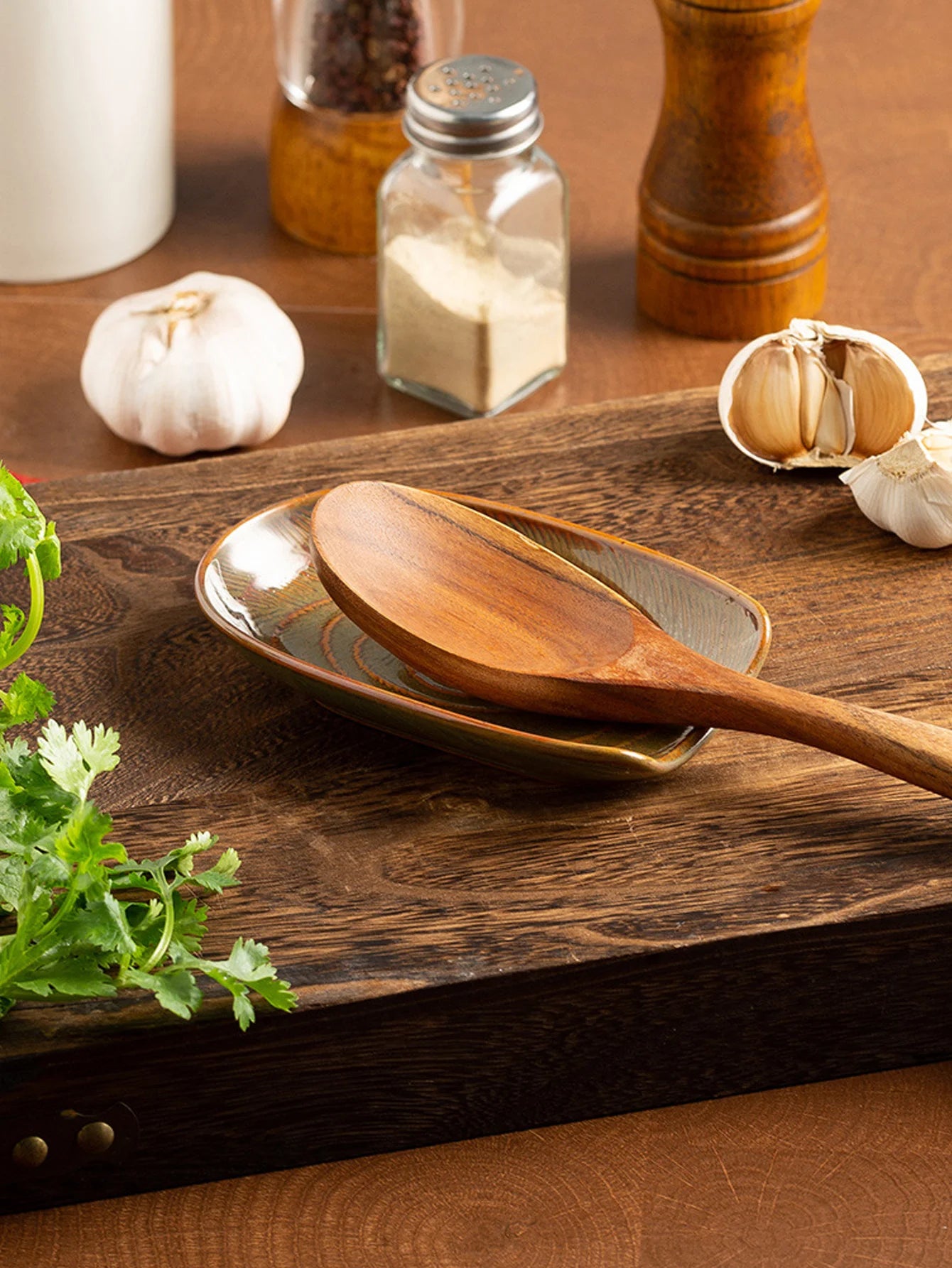 Vintage-style ceramic spoon rest in gray holding a wooden cooking spoon on a rustic kitchen board