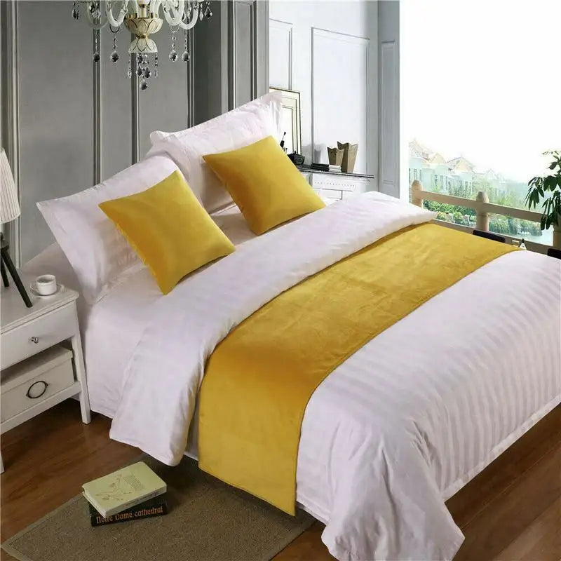 Yellow velvet bed runner and matching pillow covers on made bed in bright bedroom