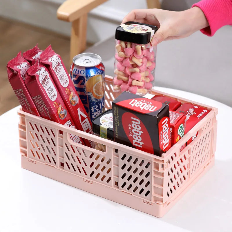 Pink foldable storage crate holding snacks and pantry items on a table