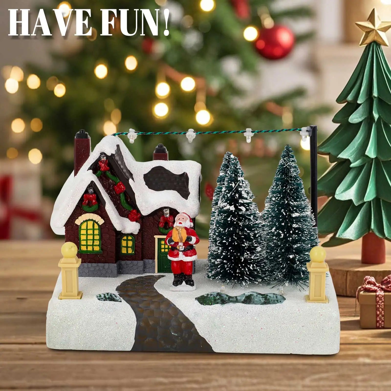 Christmas village decor with snow, Santa, and trees in front of a Christmas tree