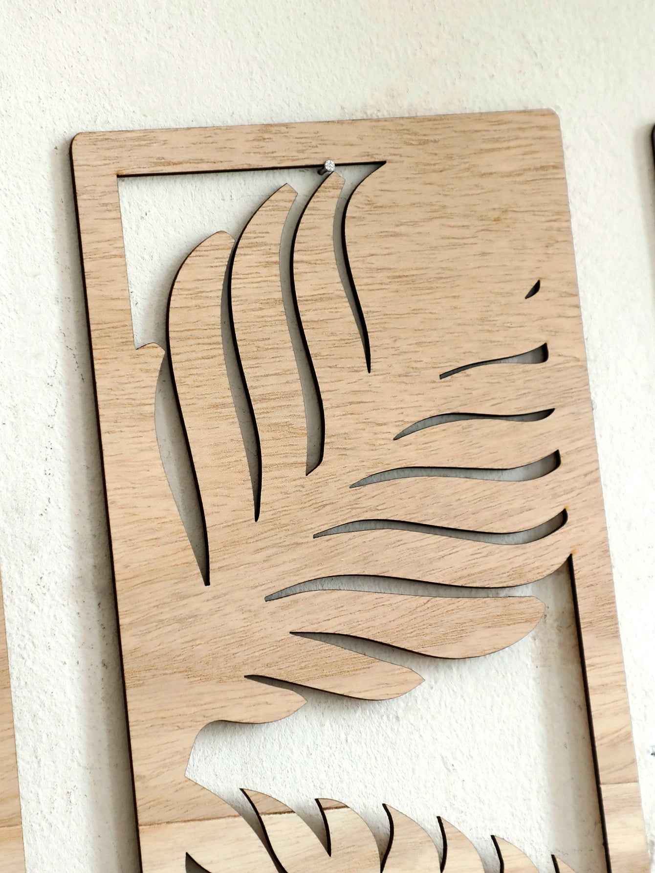 Closeup of cutout palm leaf design in natural wood wall art panel
