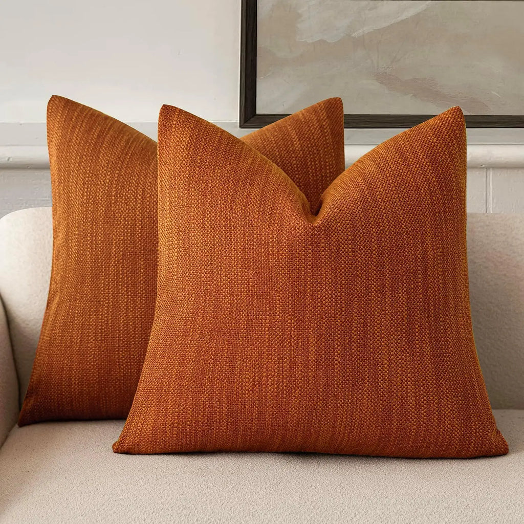 Pair of burnt orange chenille decorative pillow covers on a sofa