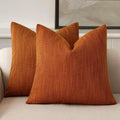 Pair of burnt orange chenille decorative pillow covers on a sofa