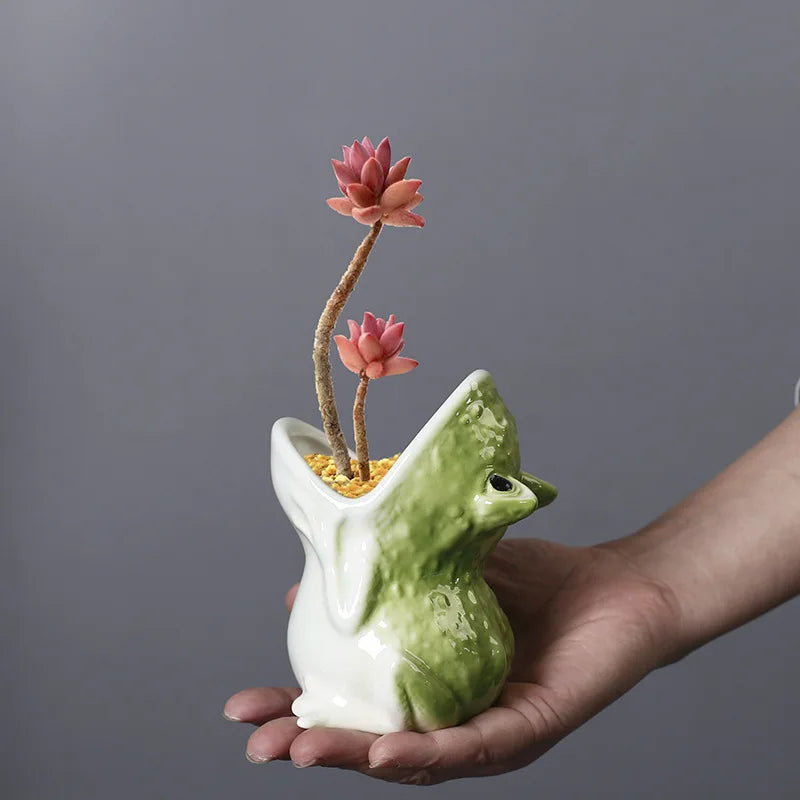 Green ceramic frog animal planter being held in hand, showing its small size