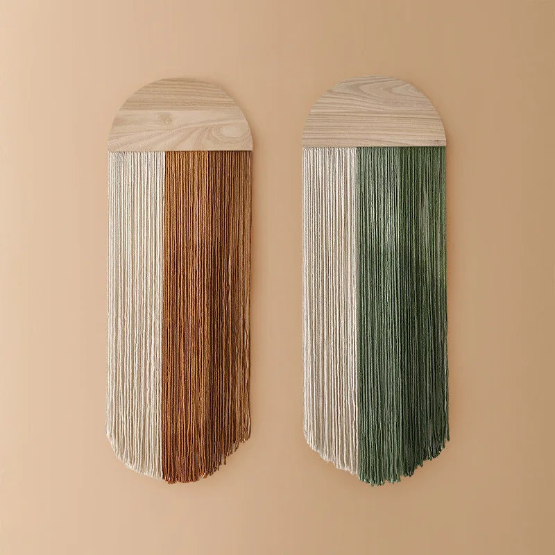 Brown and green tassel woven wall hangings with half-circle wood arch tops on a neutral wall