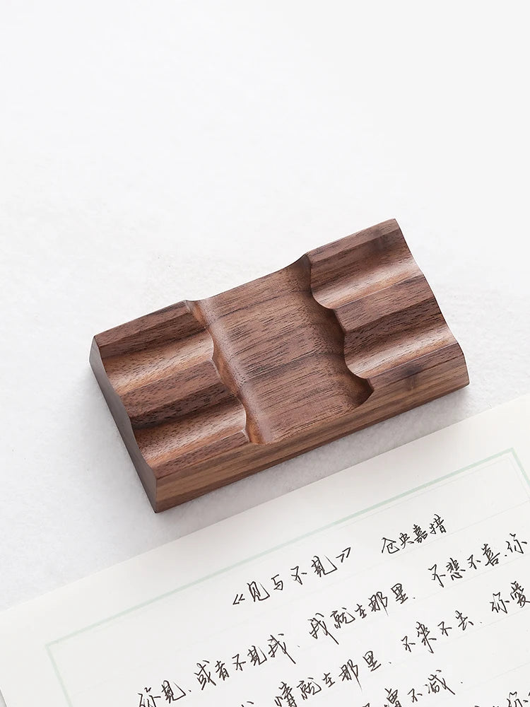 Walnut double pen holder for fountain pens next to handwritten paper
