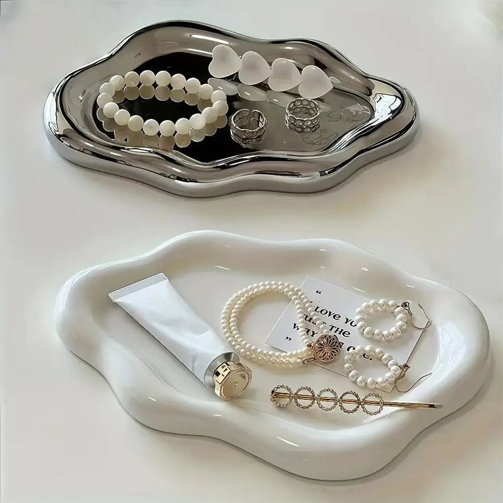 Two cloud-shaped jewelry trays in white and silver shown with rings and bracelets on a table