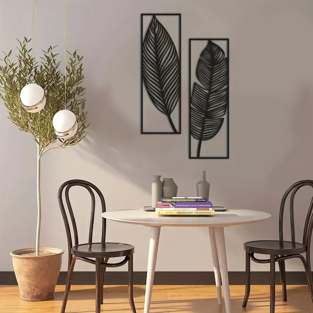 Dining area with two black metal leaf wall art panels hung vertically beside a table and chairs