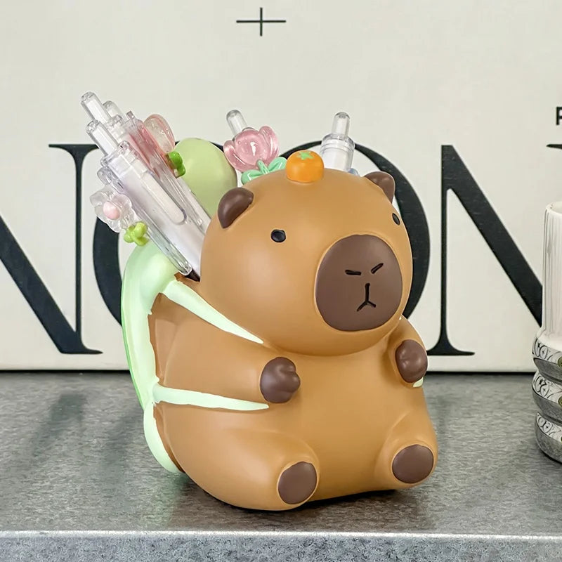 Capybara desk organizer in front of books holding pens and stationery