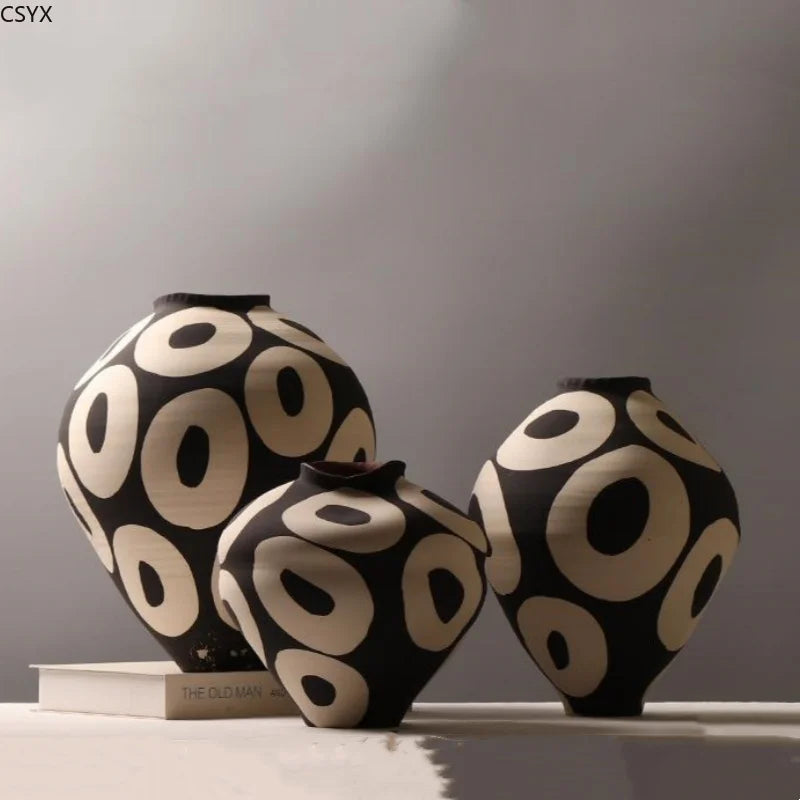 three sizes of round ceramic vases with hand-drawn geometric circles in black and cream on a tabletop
