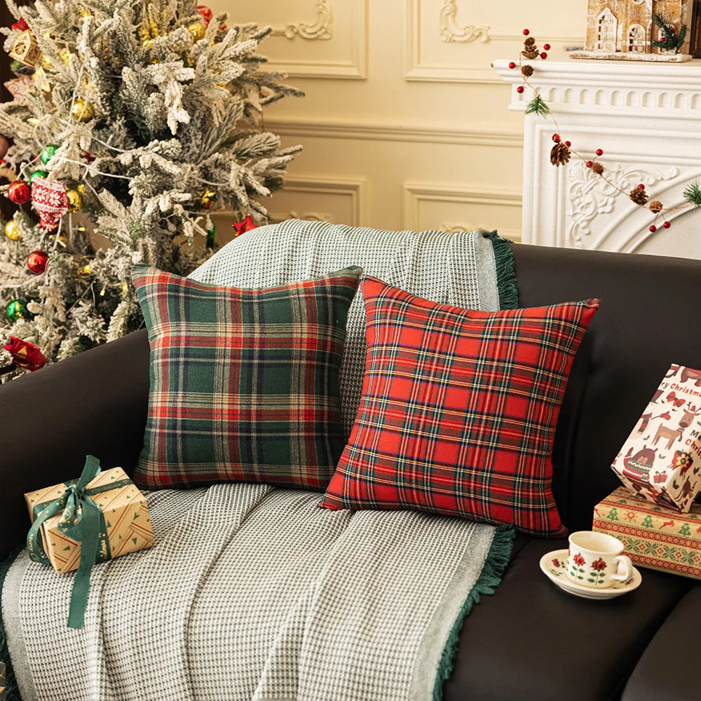 Two tartan plaid pillow covers on a sofa with holiday gifts and decor