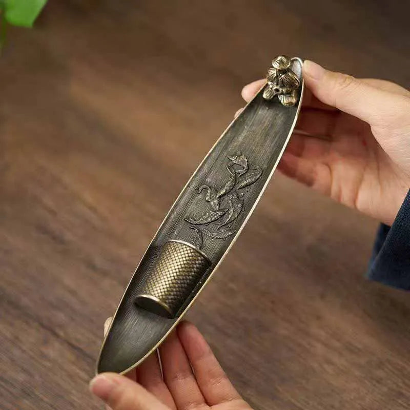 Hands holding the metal incense boat, showing size and details