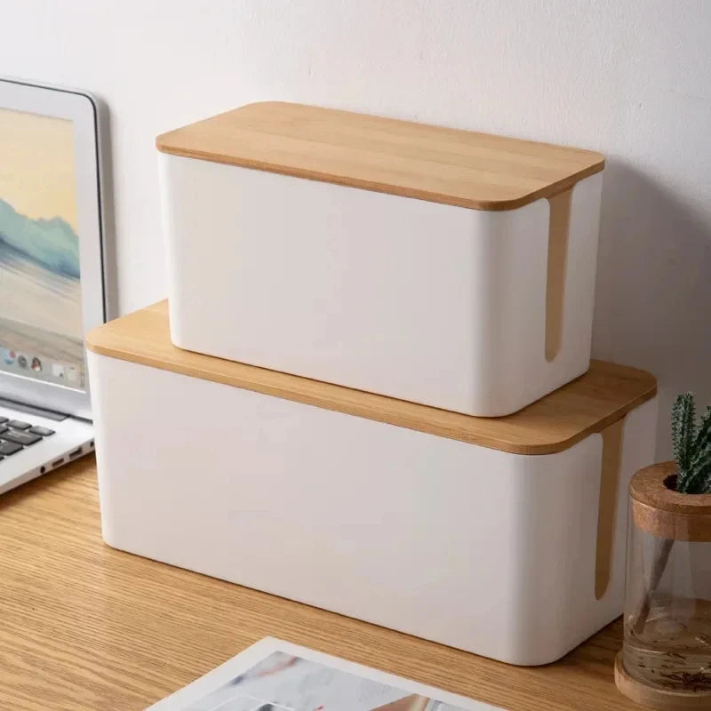 Stacked white cable boxes with bamboo lids on a desk for cord storage
