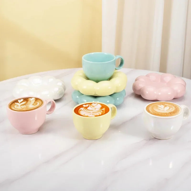 Blue, yellow, pink, and white cloud mugs and saucers with coffee and latte art in each mug