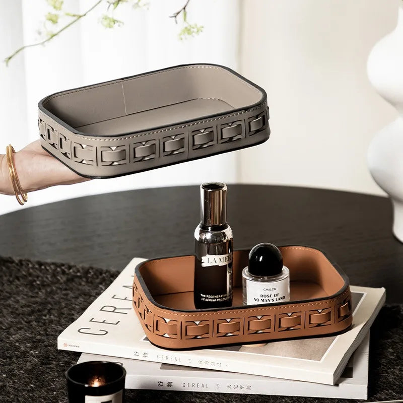 Rectangular leather vanity trays in grey and brown holding bottle and perfume, styled on a table