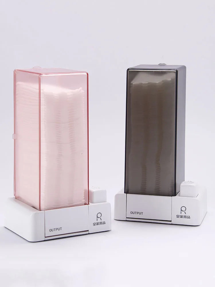 Automatic cotton pad dispensers in pink and grey arranged side by side, showing their compact rectangular shape