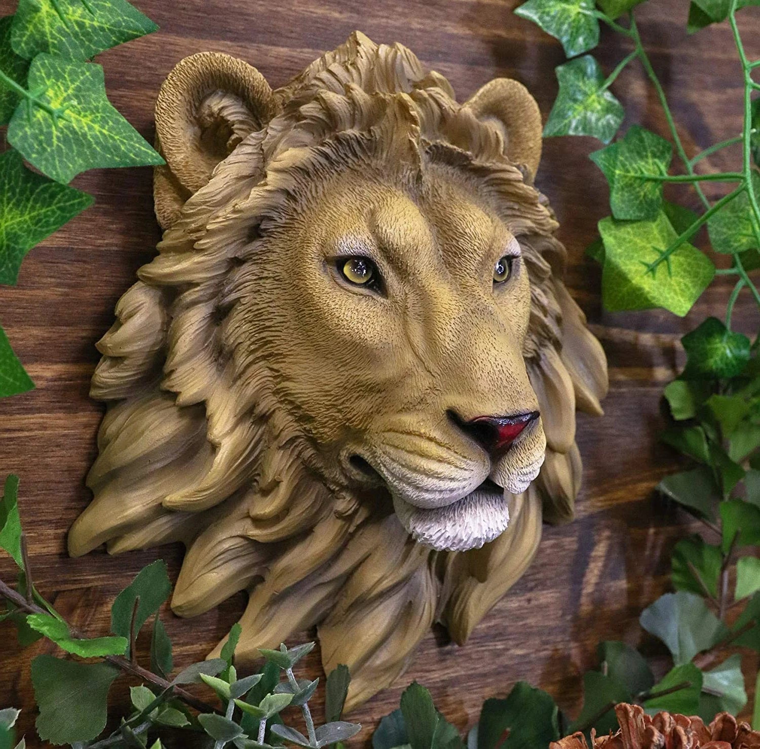 Realistic lion head wall sculpture in resin displayed against a wood wall with greenery