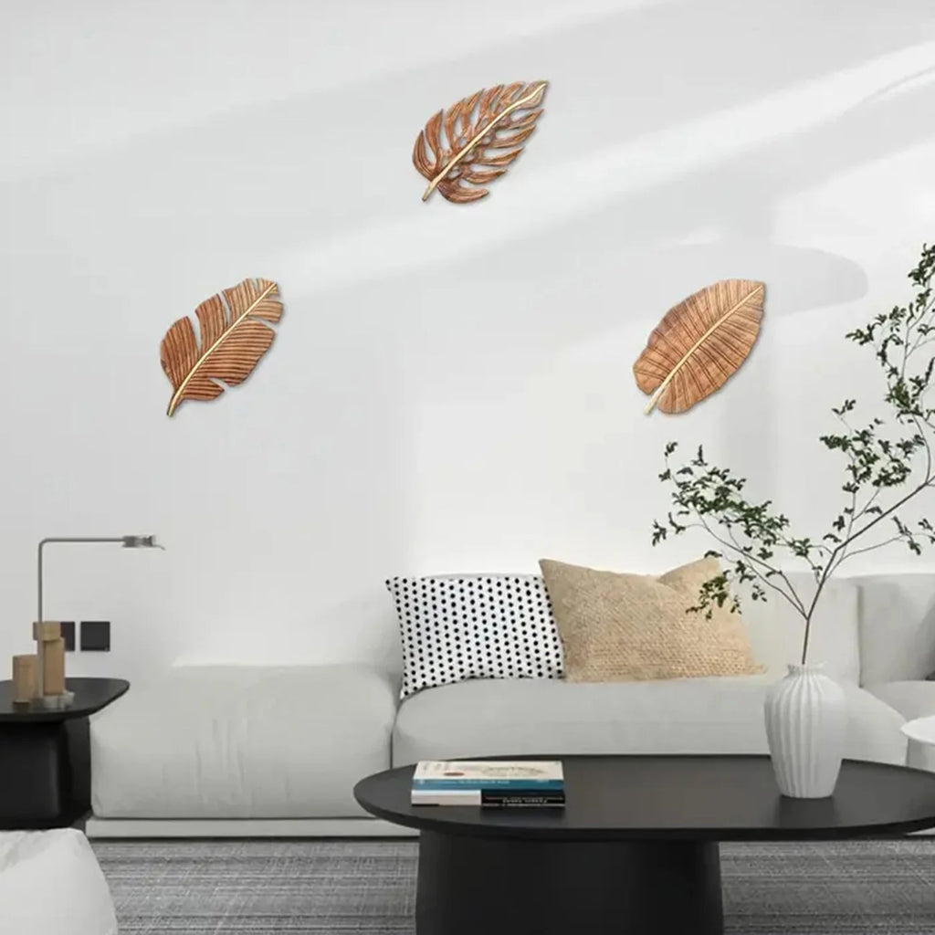 Wooden leaf wall art set of three displayed on a minimalist white living room wall