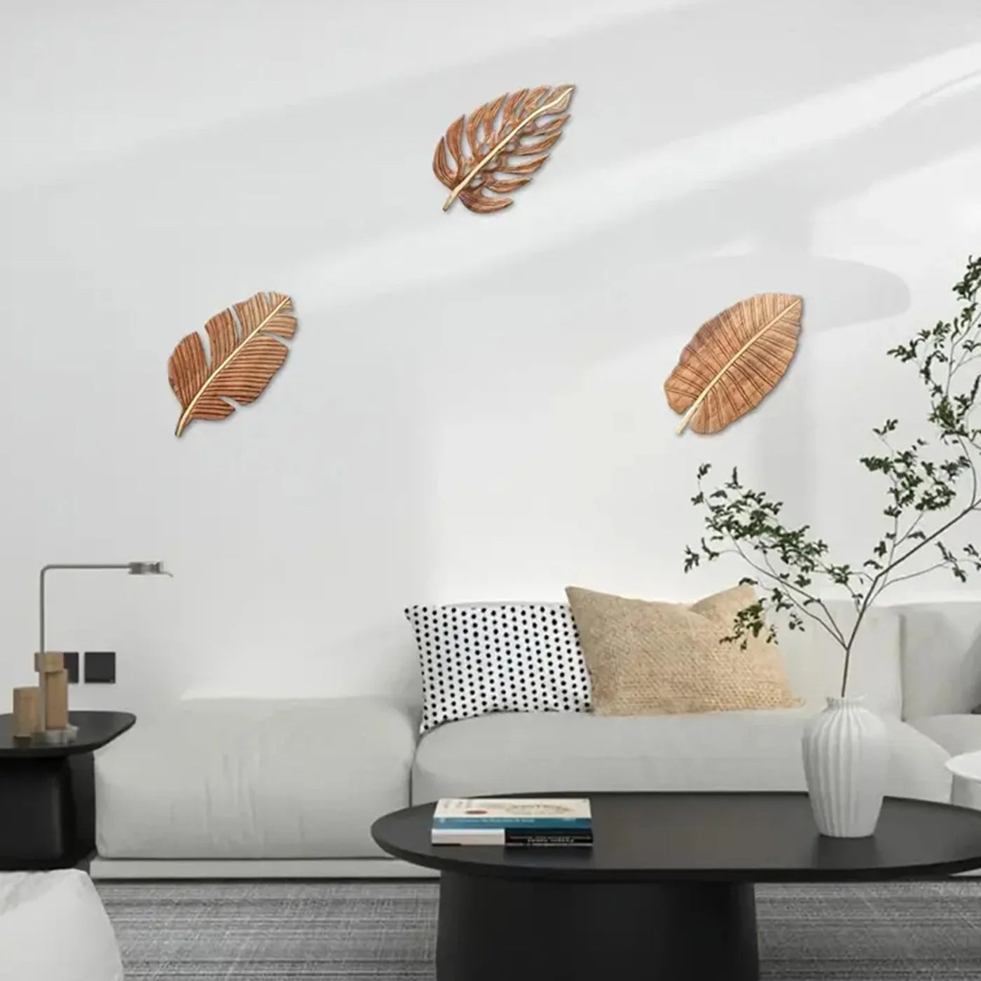 Wooden leaf wall art set of three displayed on a minimalist white living room wall