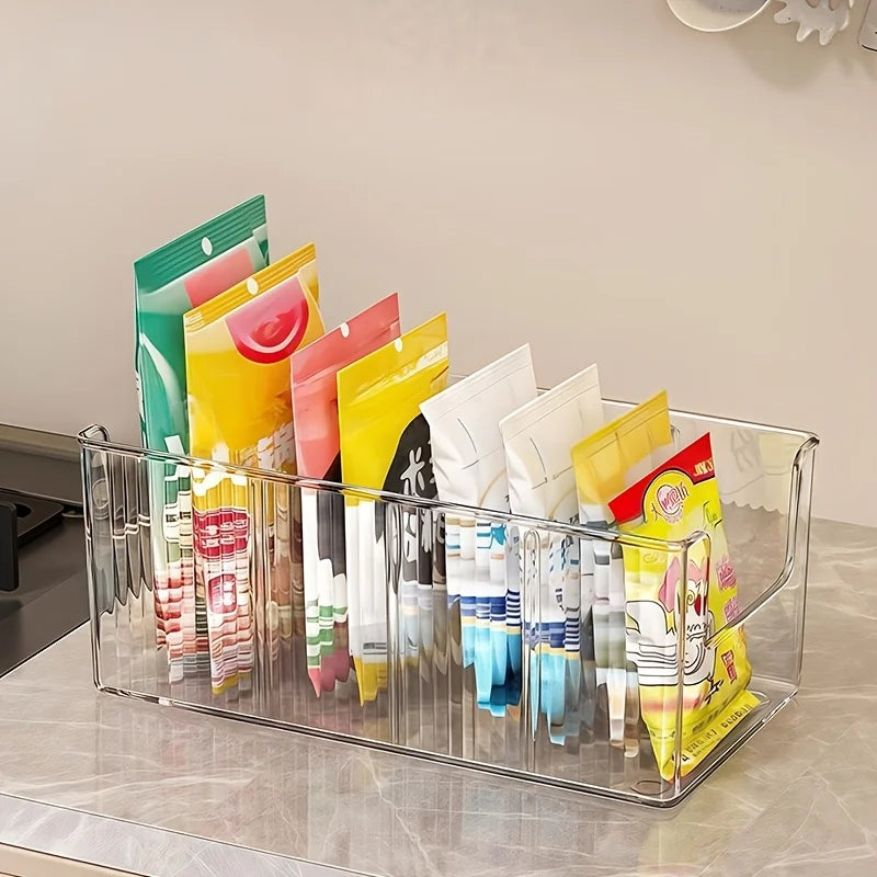 Empty clear ribbed plastic storage bin with several snack packets