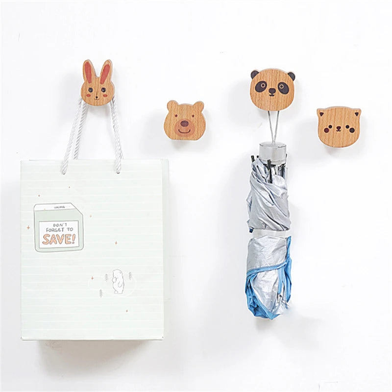 Wooden animal wall hooks holding a bag and an umbrella on a bright wall.
