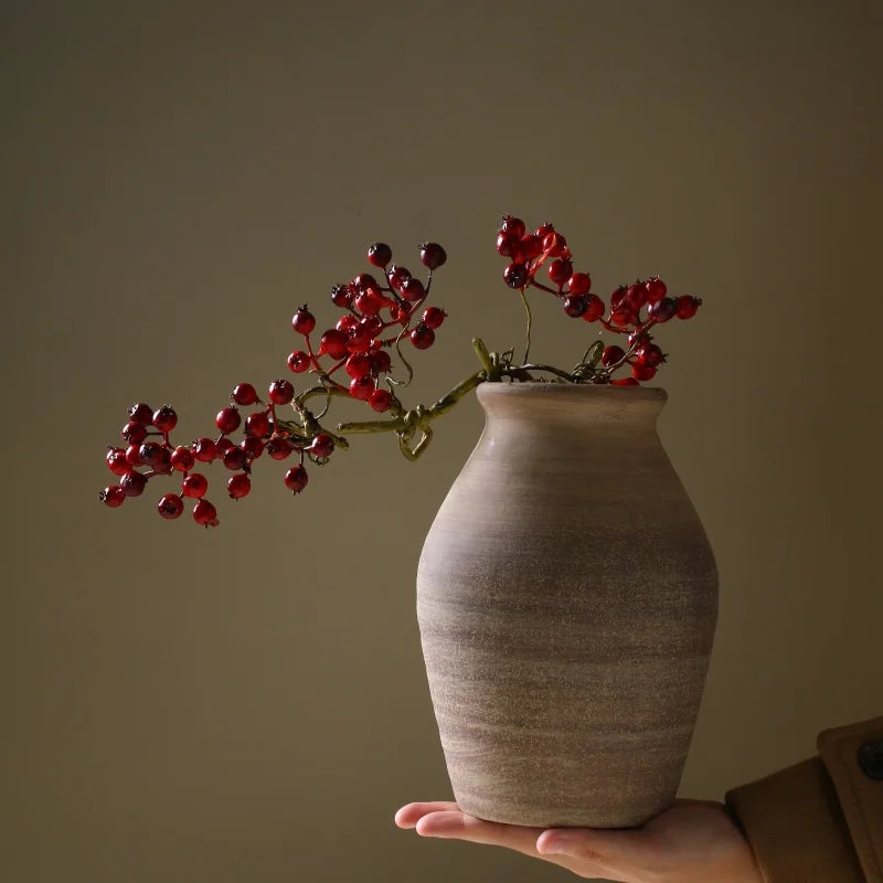 Hand holding vintage-inspired ceramic vase with dried branches