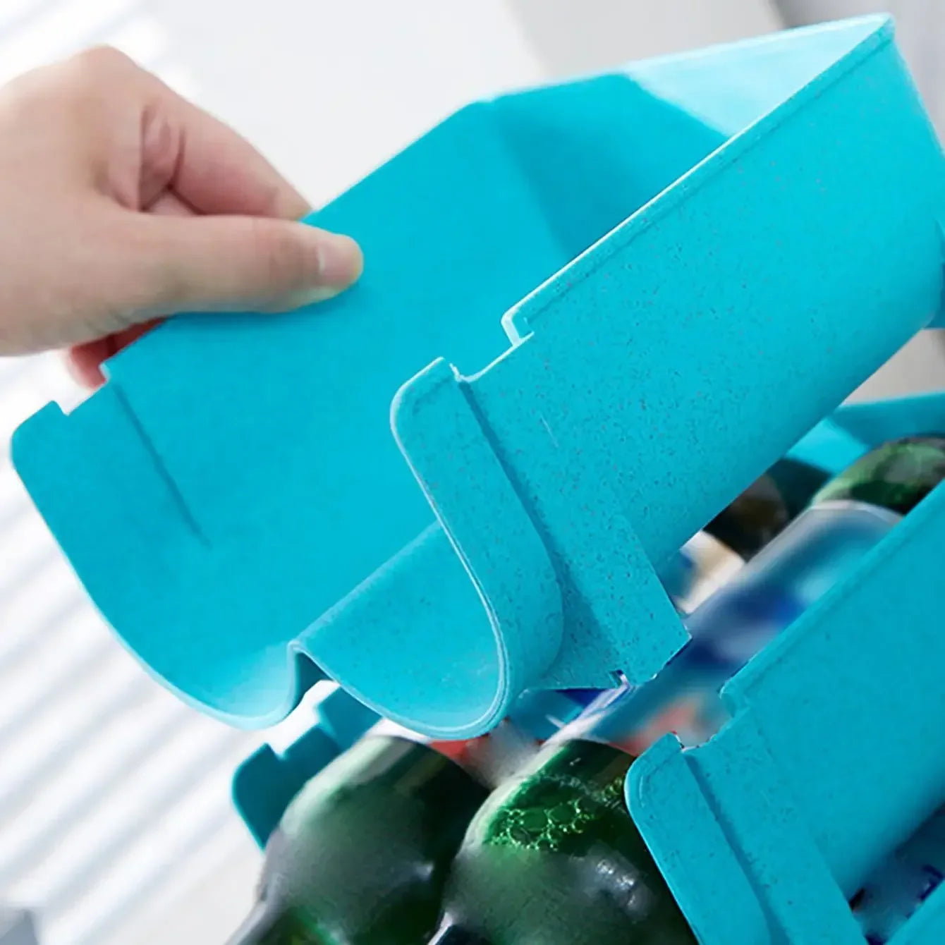 close up of blue plastic stackable bottle organizer rack being lifted for modular stacking