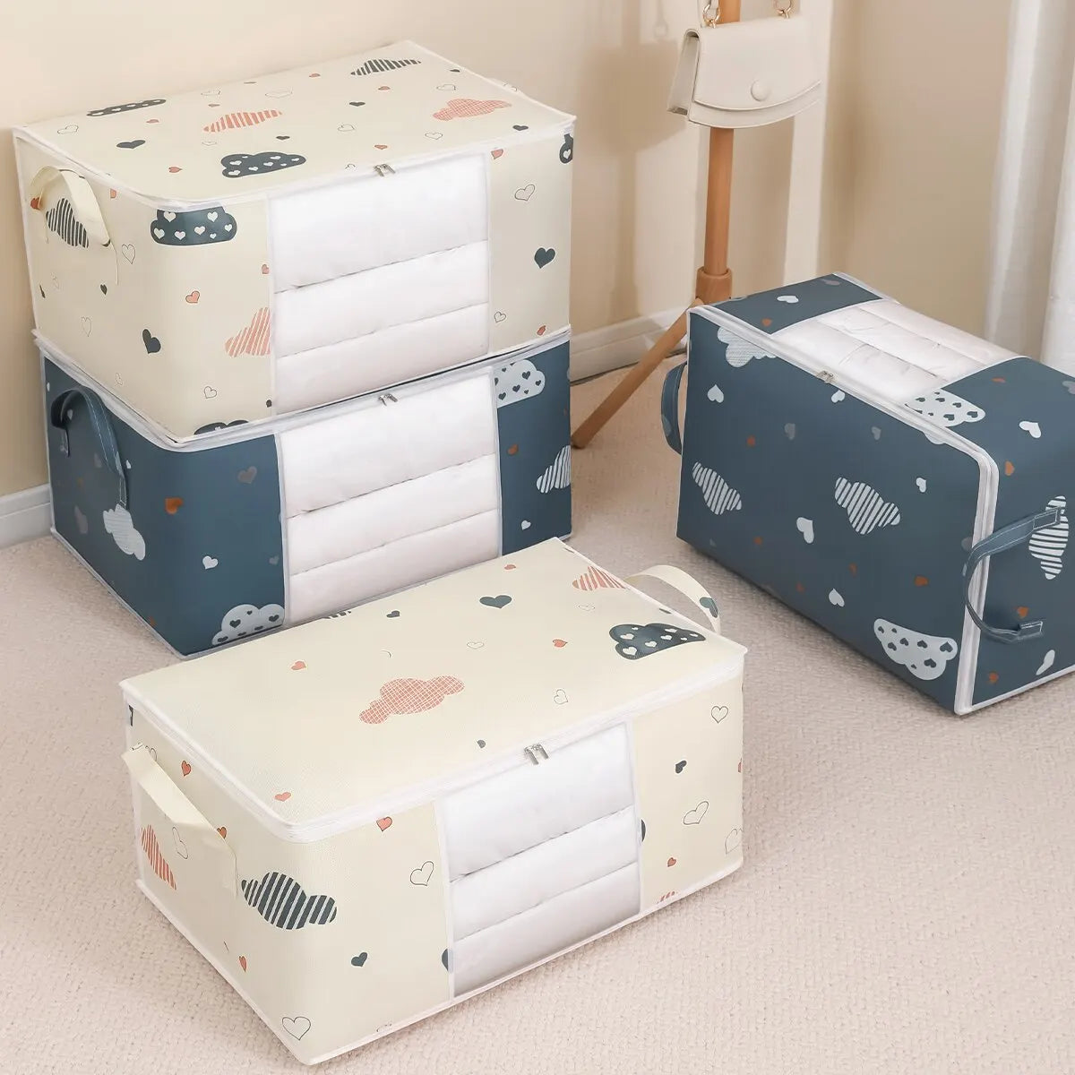 Assorted blue and beige cloud print foldable storage bags shown in a bedroom, showcasing both medium and large sizes.