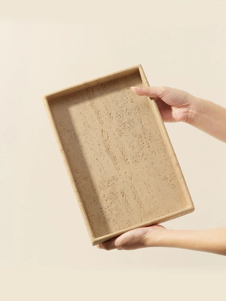 Hands holding a rectangular travertine-style bathroom tray