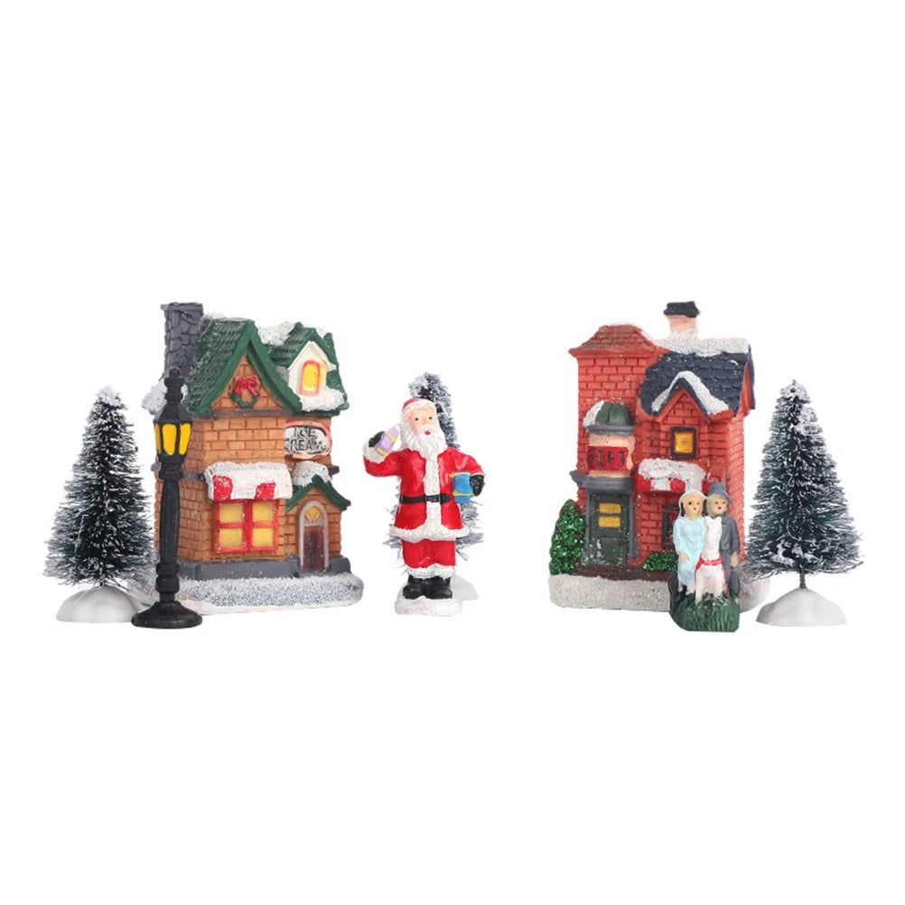 Two Christmas houses, snow trees, Santa, street lamp, and family figurine from village set on white background