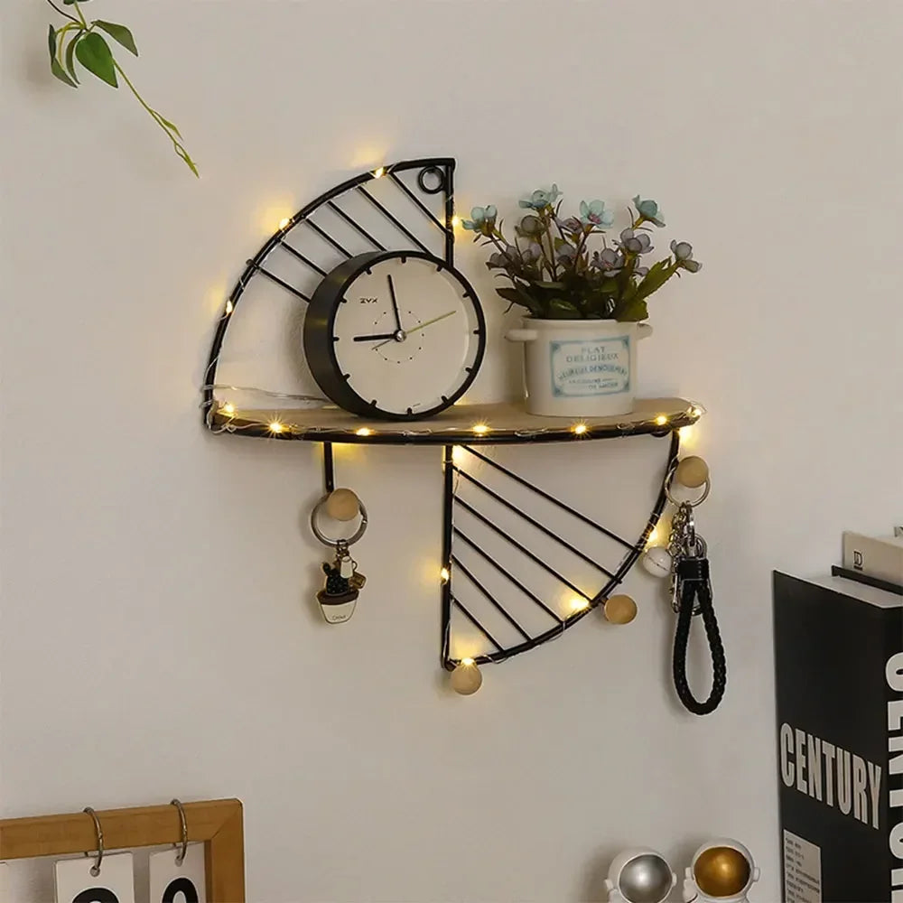 Semi-circular black metal wall shelf with a clock, plant, and items hanging from hooks on a wall.