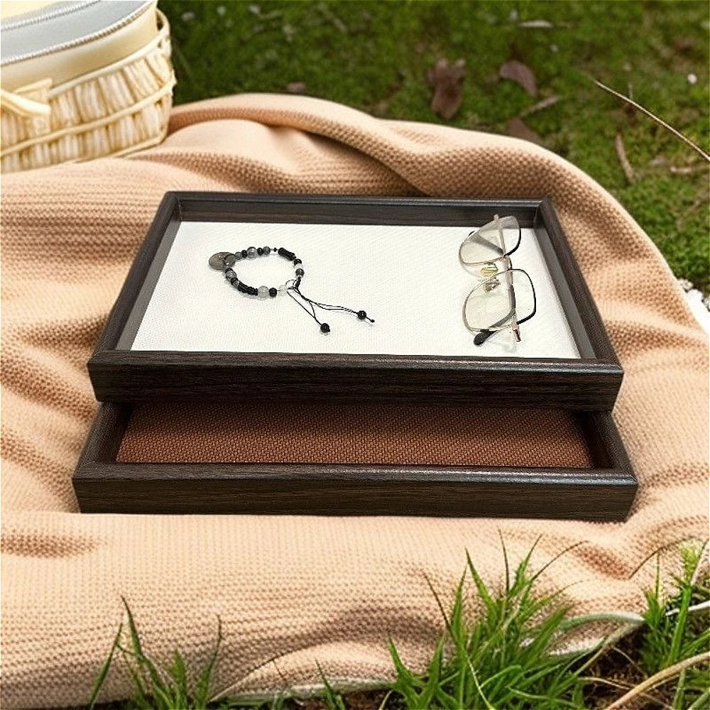 White and brown faux leather organizing trays on a picnic blanket outdoors with glasses and bracelet
