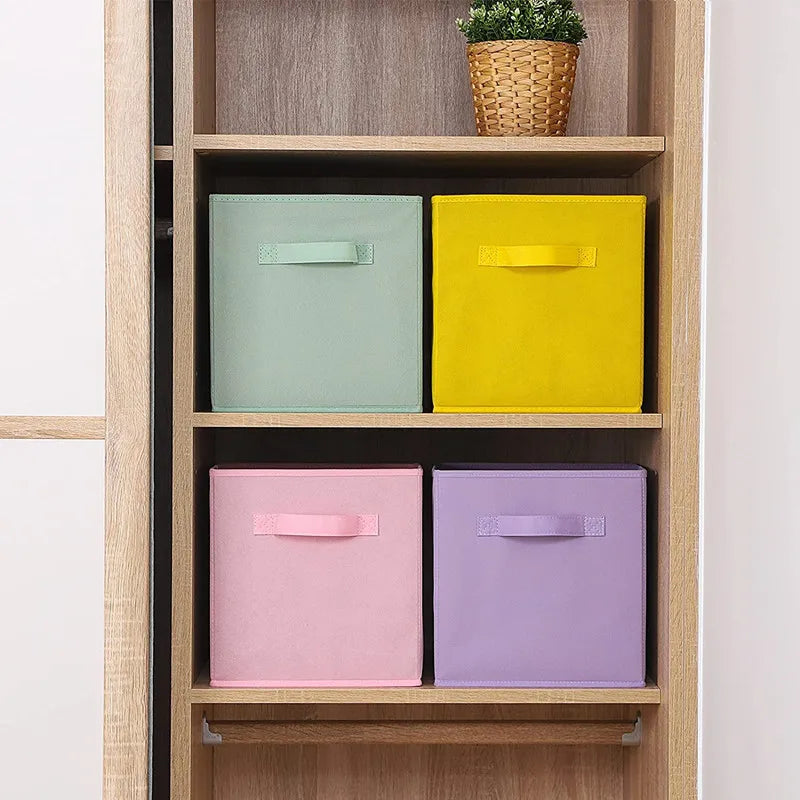 Four colorful fabric storage bins arranged on shelves in a wooden closet