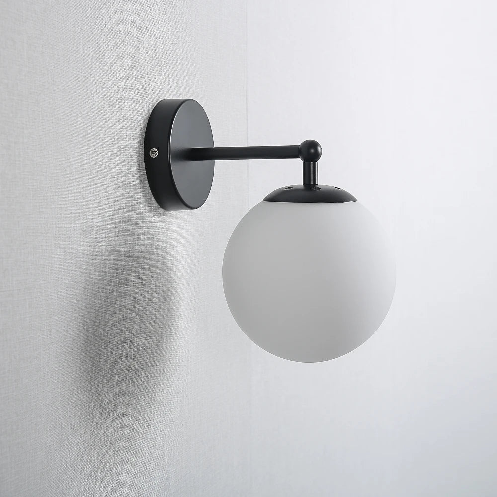 Side view of globe wall sconce with black finish and frosted glass shade