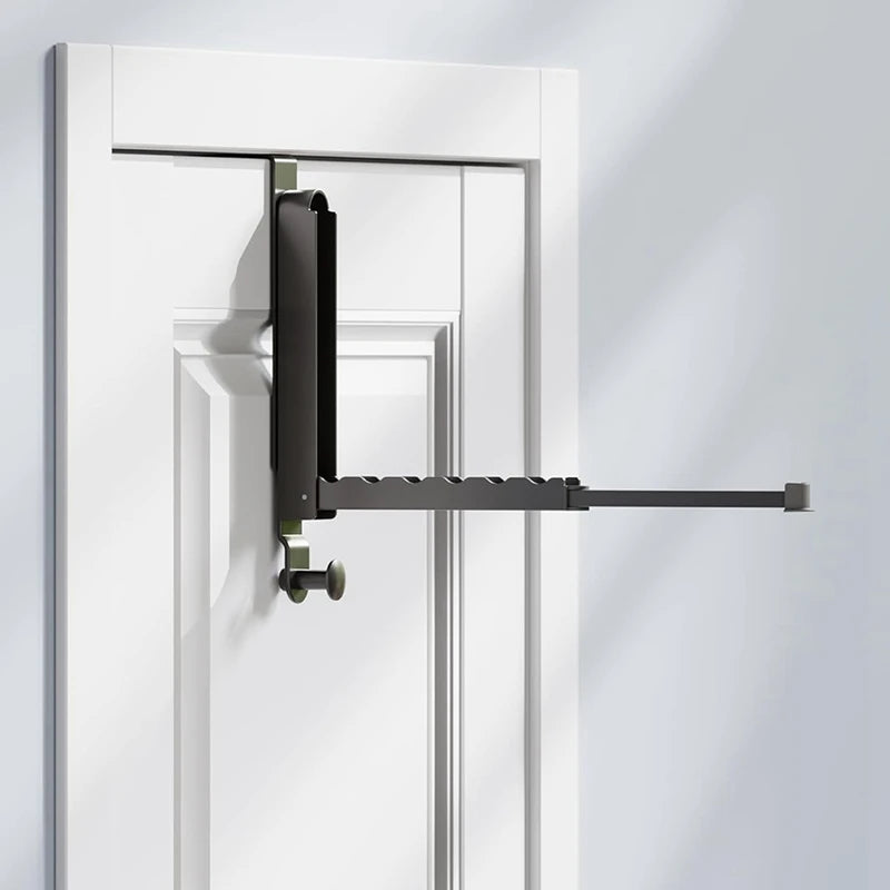 retractable over-the-door drying rack extended on a white door in a bright room