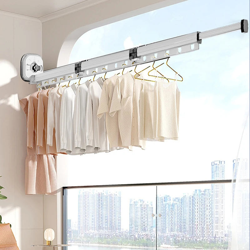 White folding suction cup clothes drying rack mounted above a window with shirts and tops hanging on multiple hooks.