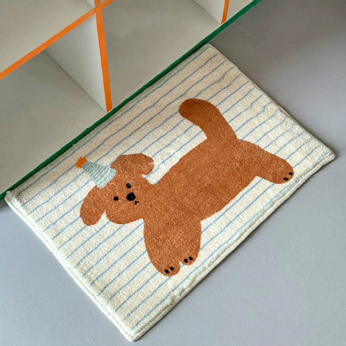 Striped fleece bathroom mat with brown cartoon puppy print placed near a shelf