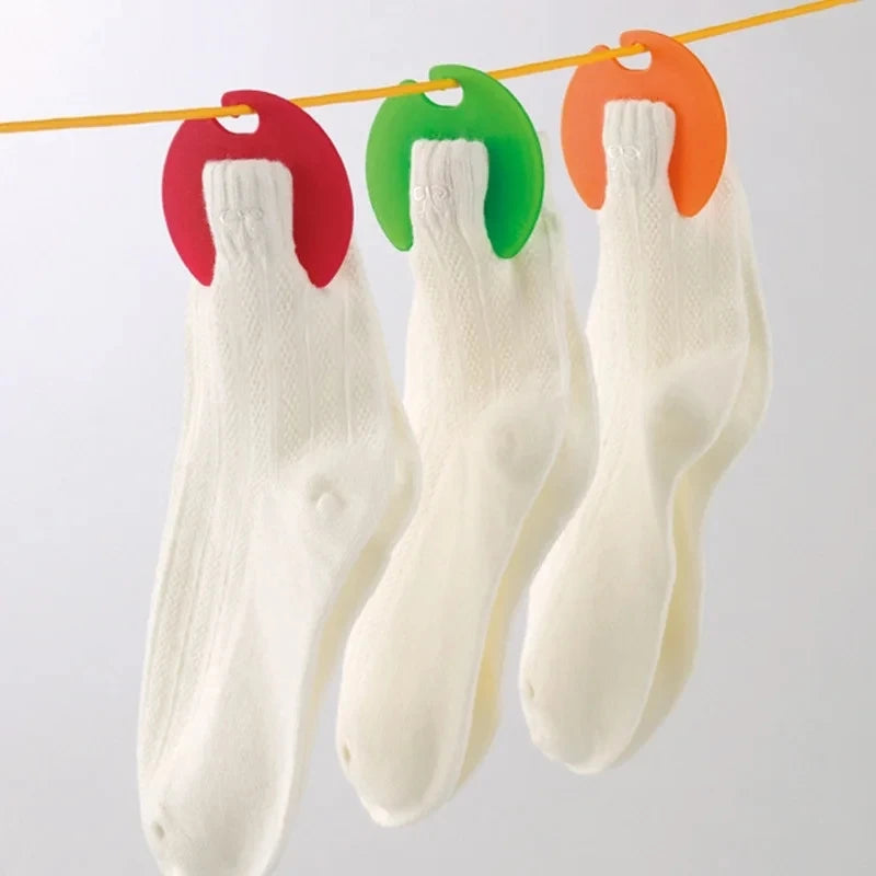 Three white socks clipped with red, green, and orange sock clips hanging on a laundry line