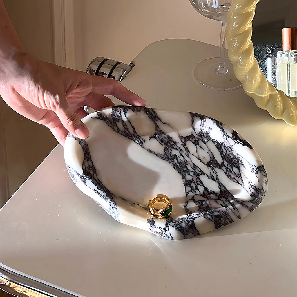 Hand placing ceramic marble tray with a ring on a dresser