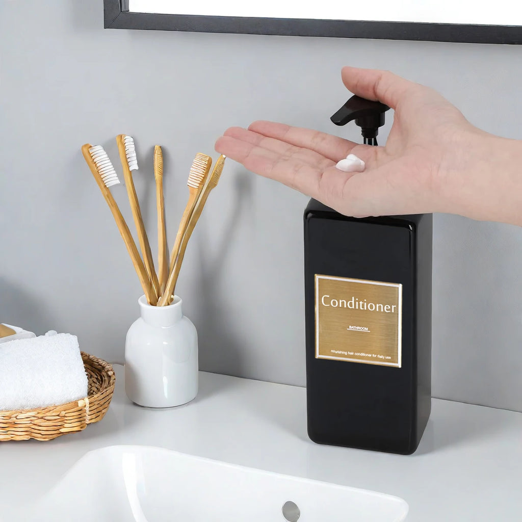 Hand dispensing conditioner from a black rectangular pump bottle beside a sink