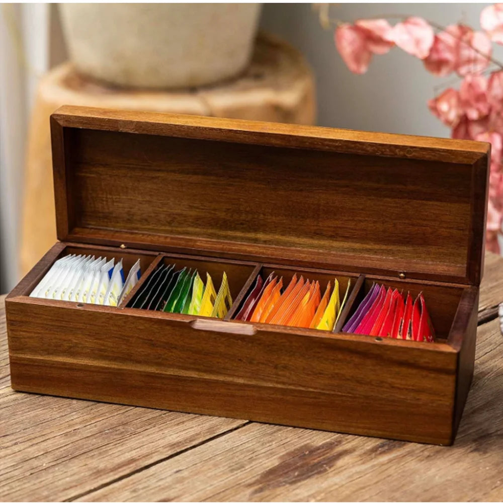 Acacia wood tea bag organizer with 4 compartments and assorted tea packets, styled beside pink flowers