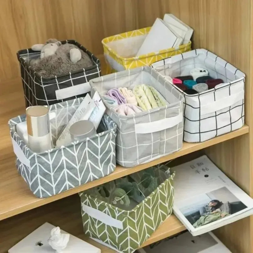 Multiple fabric storage bins with grid and leaf patterns holding assorted household items on wooden shelves