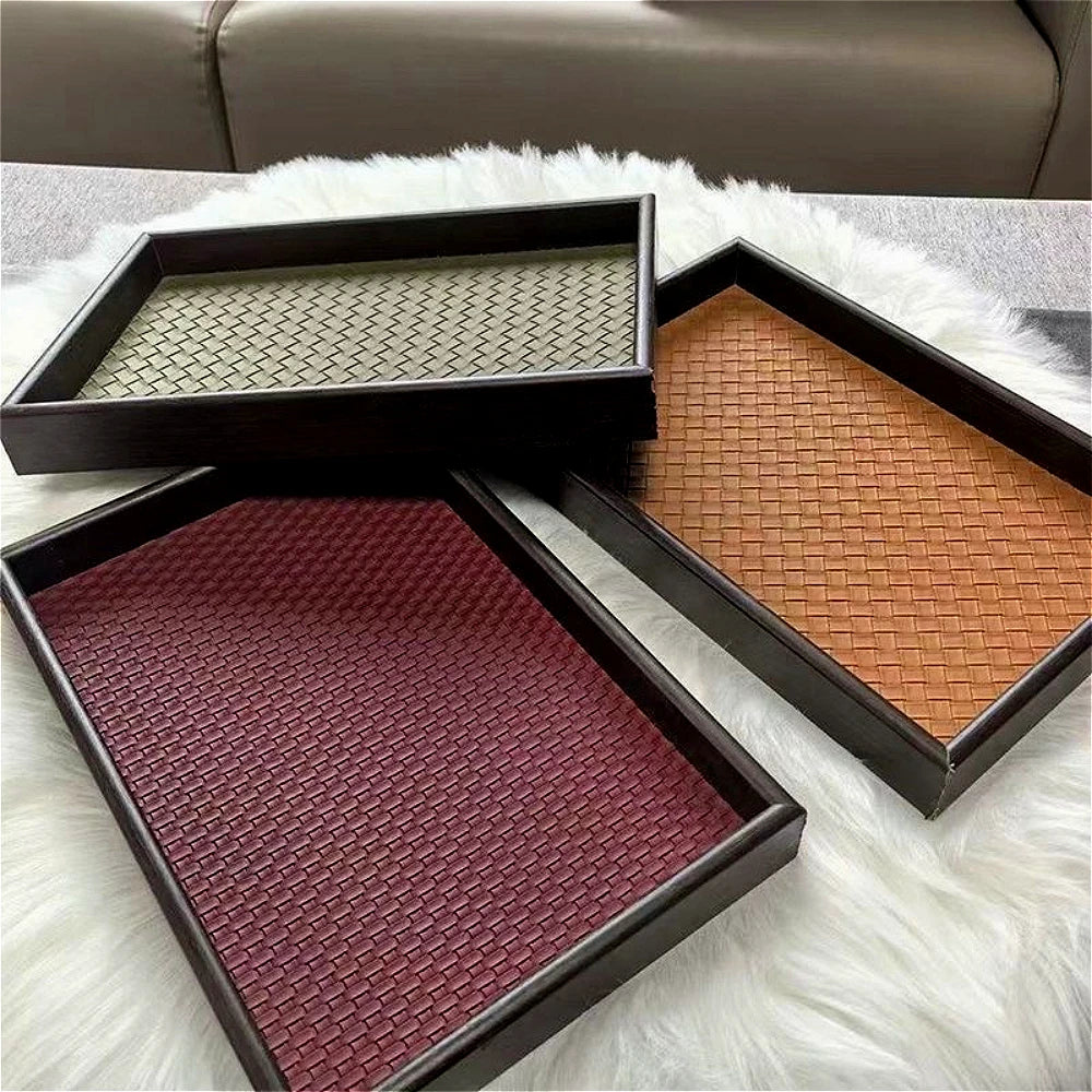 Three rectangular storage trays in green, brown, and red faux leather on a white rug