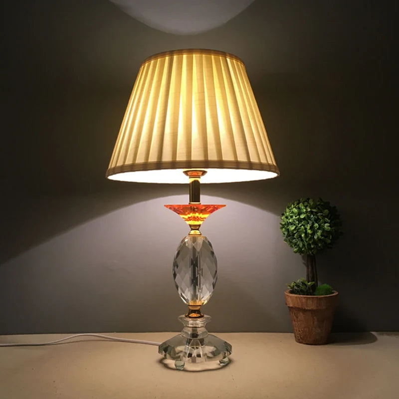 Pleated fabric lampshade on a lit bedside table lamp