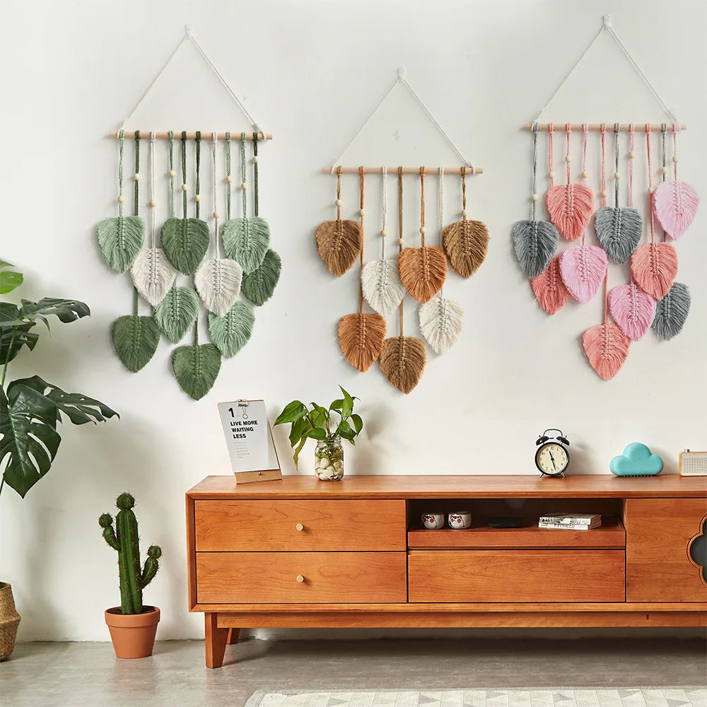 Three color options of leaf tapestry wall hangings (green, khaki, pink) displayed together on white wall